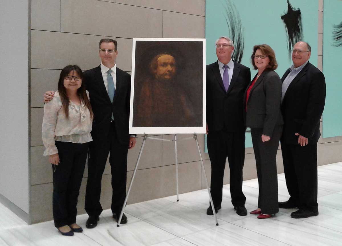 Judge Clarkson and guests flank a portrait of Rembrandt.